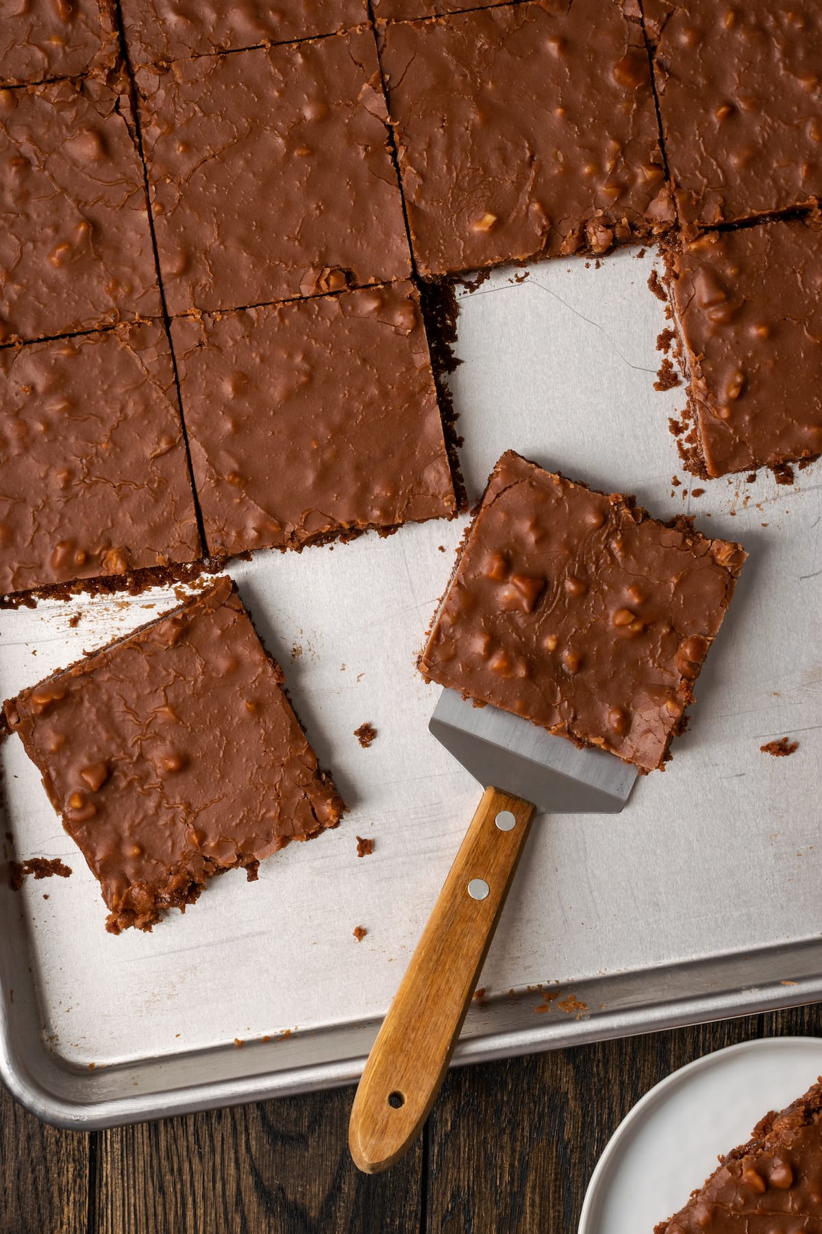 Overhead view of a slice of Texas sheet cake being served from a sheet pan with a spatula.