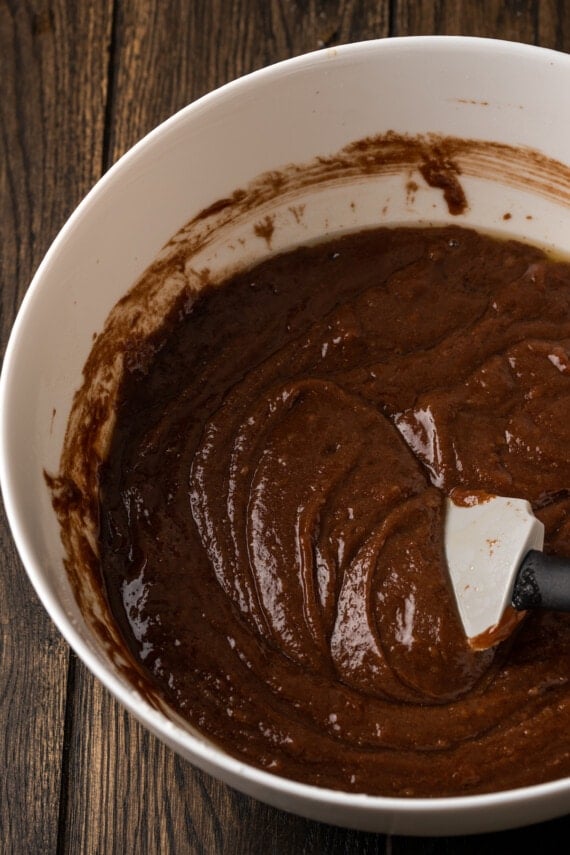 Chocolate cake batter in a large bowl with a rubber spatula.