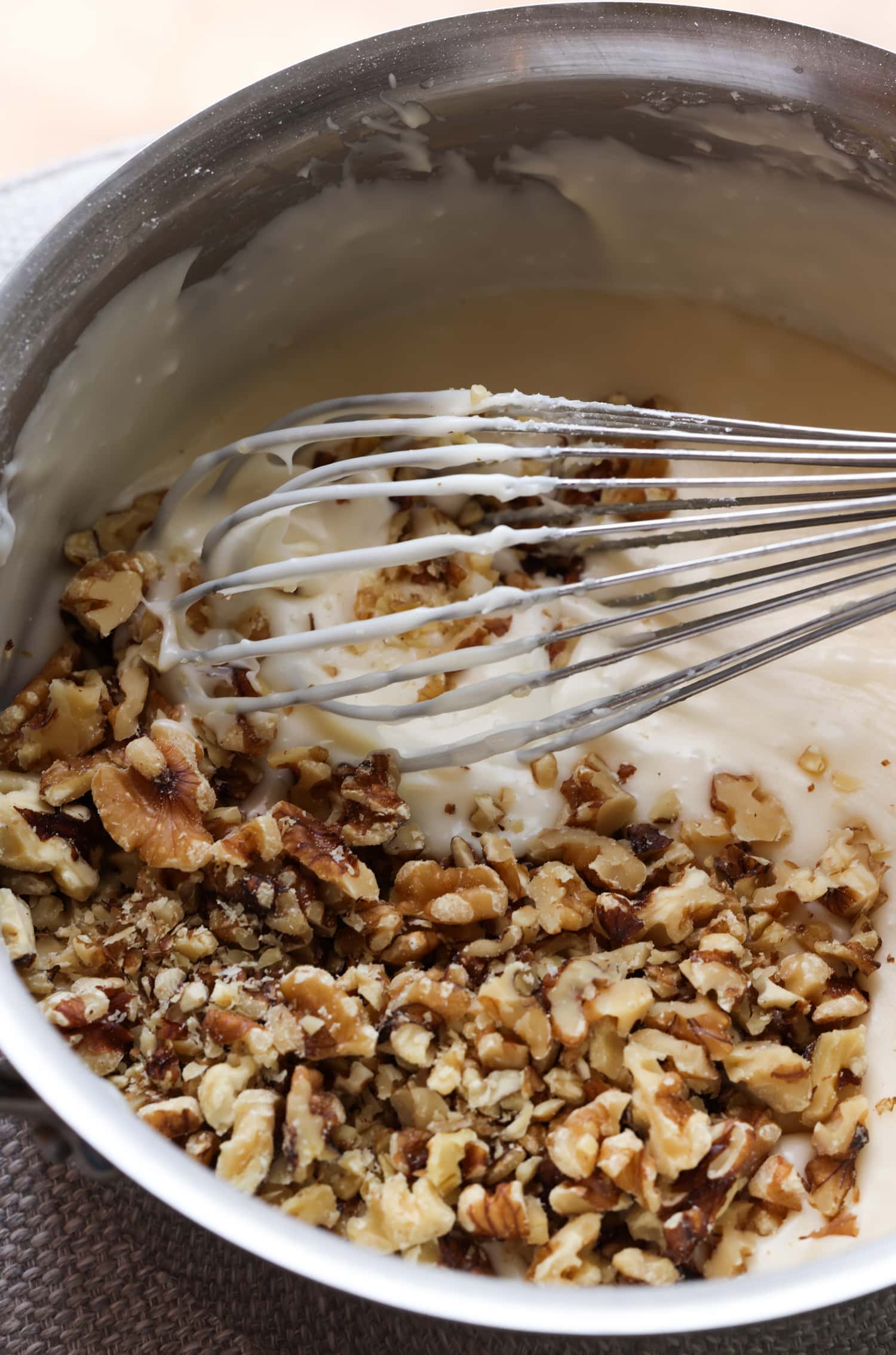 Mixing walnuts into white icing with a whisk