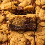Close up of baked brookies with one brookie propped up to show the layers of cookie and brownie.