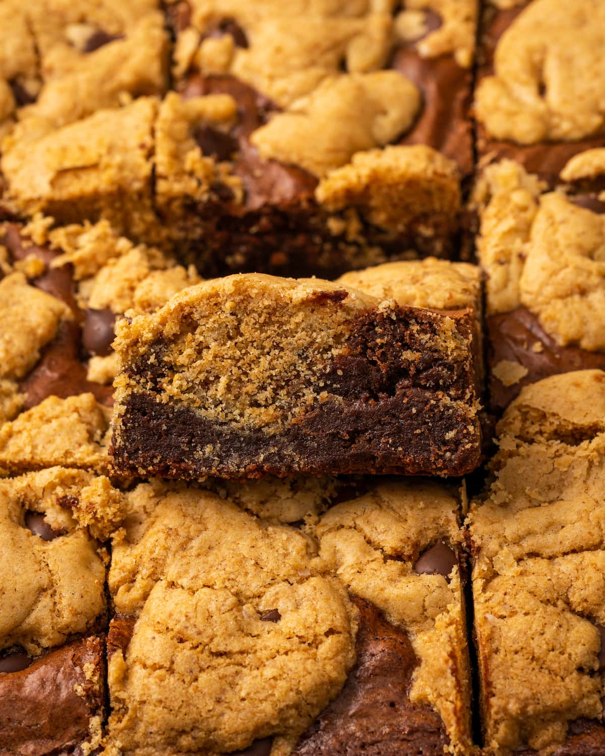 Close up of baked brookies with one brookie propped up to show the layers of cookie and brownie.