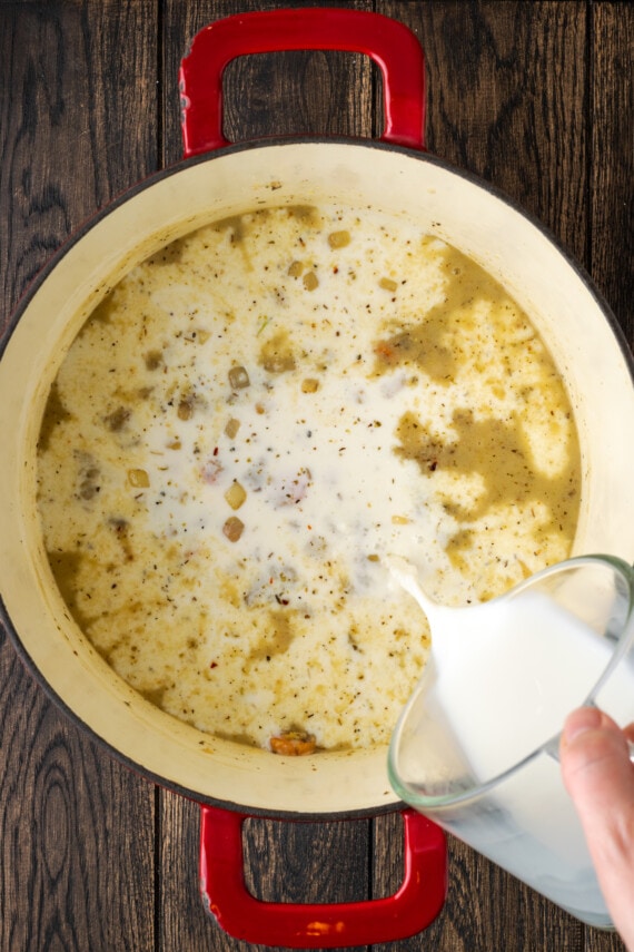 Milk poured into a pot with sauteed veggies and chicken stock.