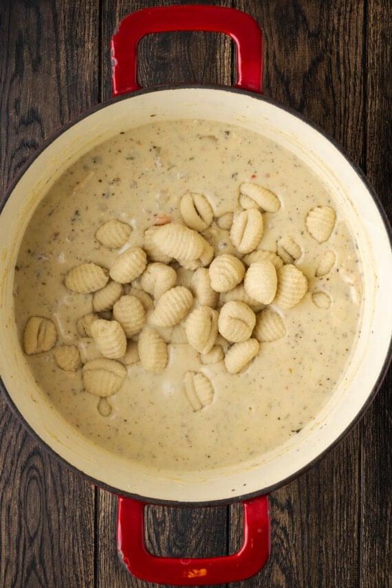 Frozen gnocchi added to a pot of creamy chicken soup.