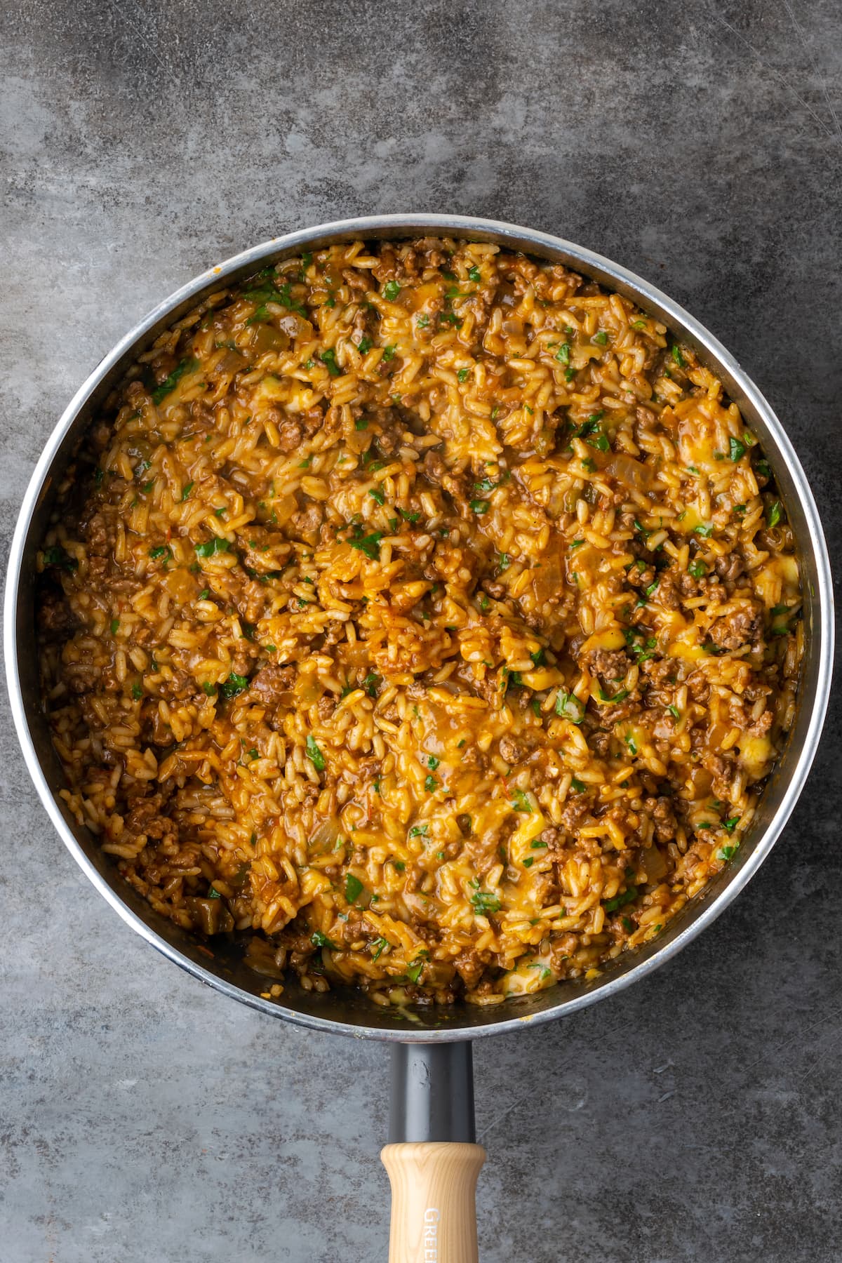 Finished taco rice topped with melted cheese in a skillet.