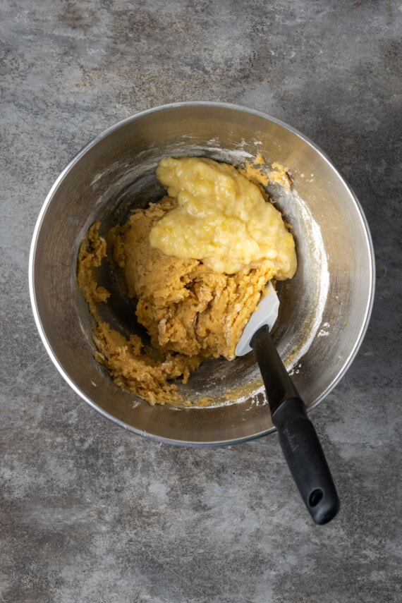 Mashed banana added to blondie batter in a mixing bowl.