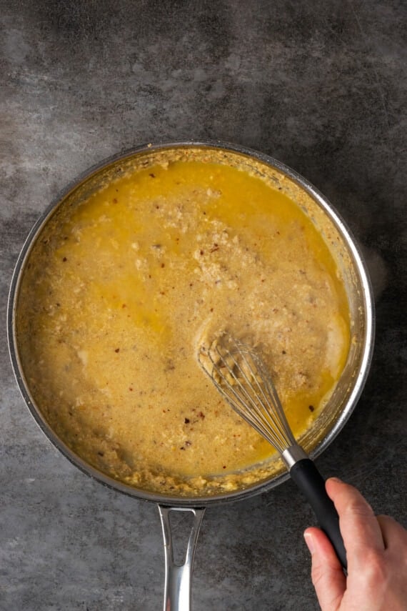 Caesar pasta sauce ingredients whisked together in a skillet.