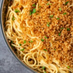 Close up of Caesar pasta in a skillet topped with garlic breadcrumbs and parsley.