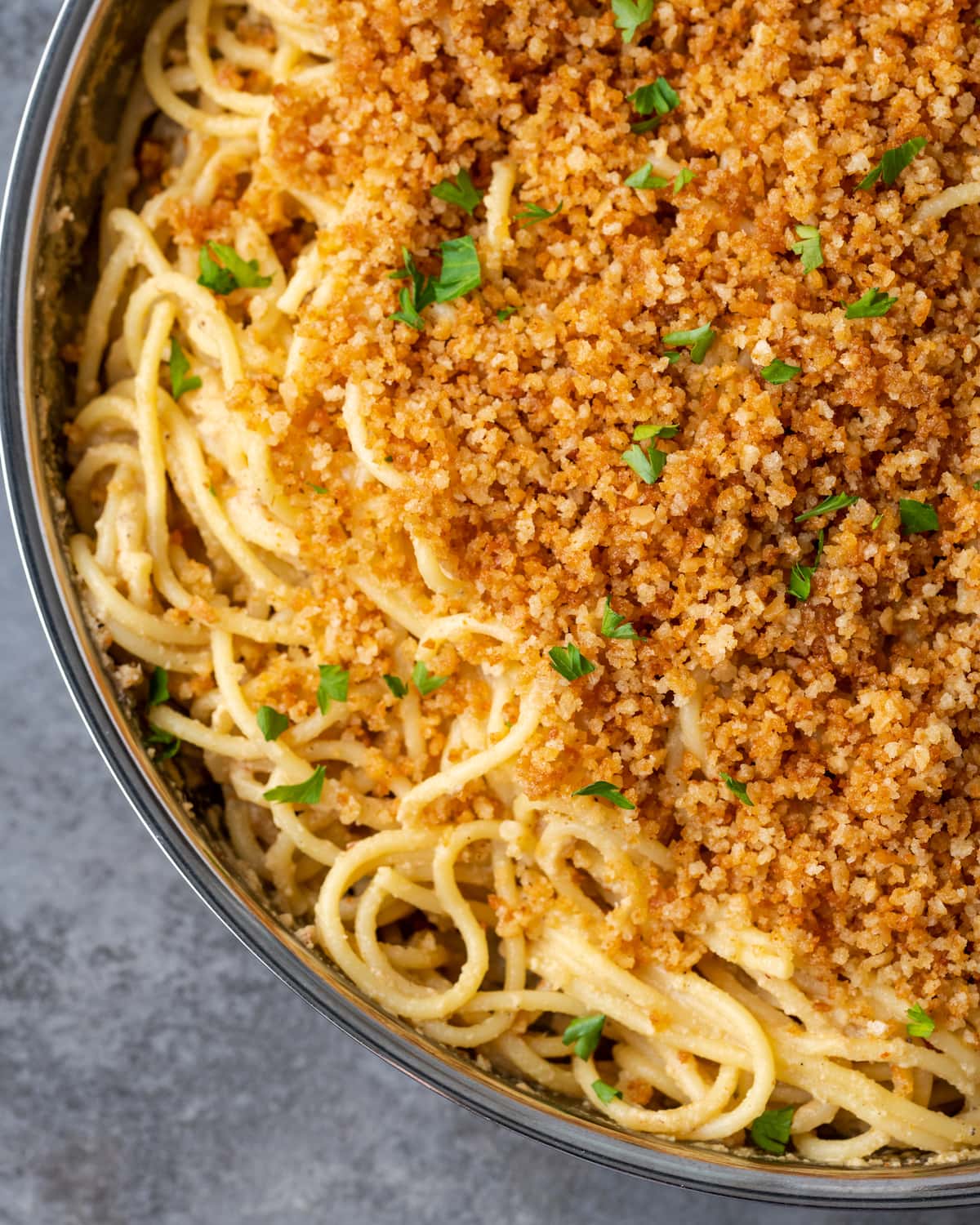 Close up of Caesar pasta in a skillet topped with garlic breadcrumbs and parsley.