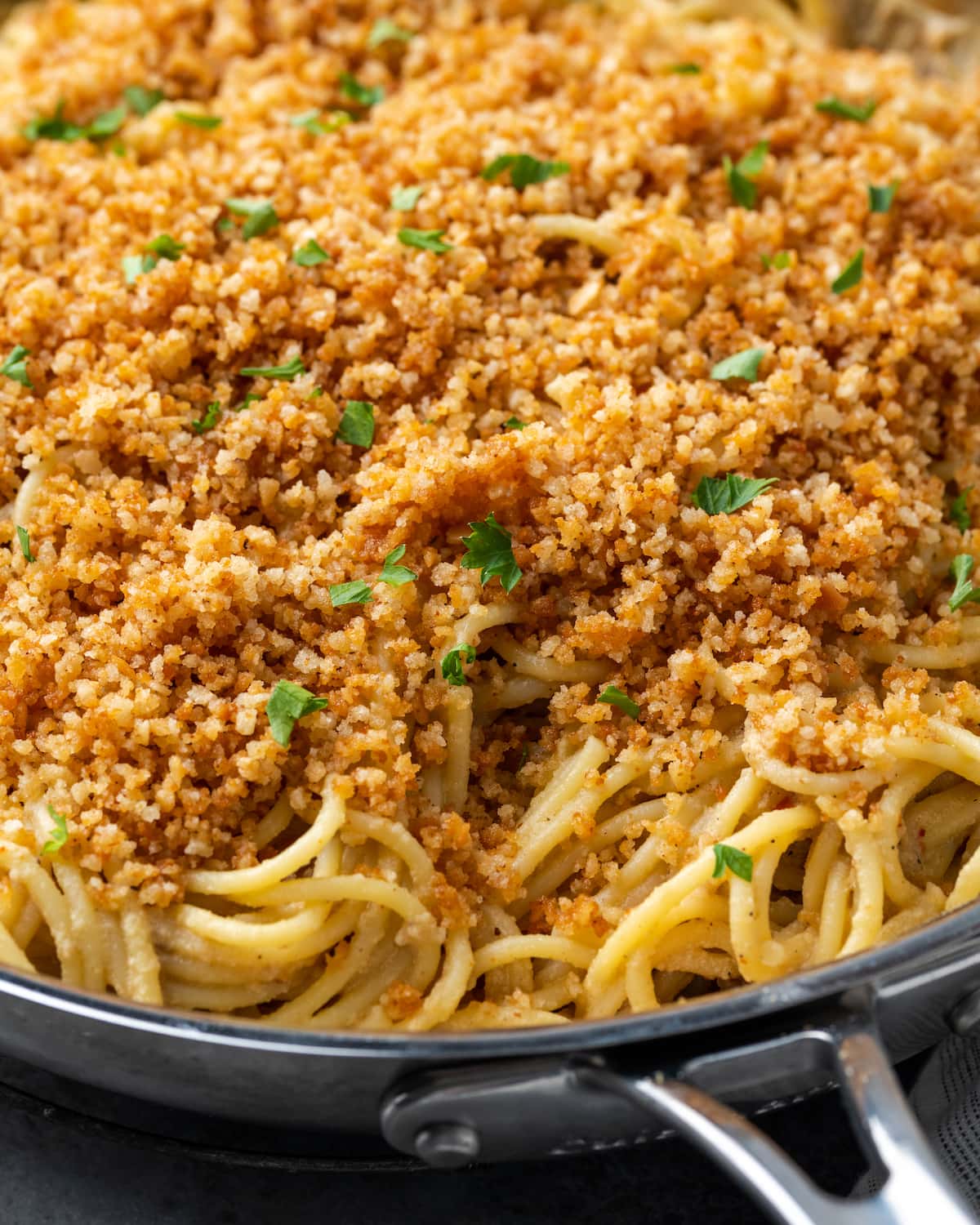 Close up of Caesar pasta in a skillet topped with garlic breadcrumbs and parsley.