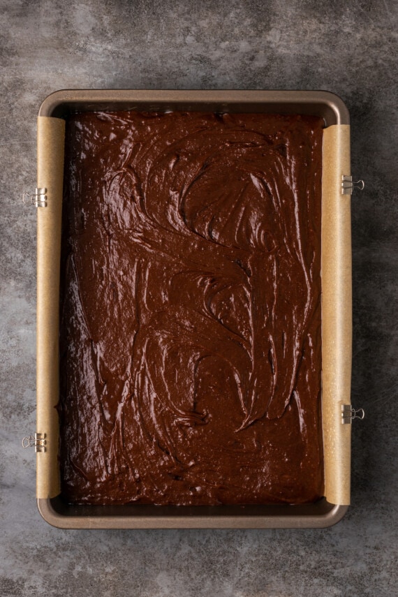 Overhead view of brownie batter in a 9x13 lined baking pan.