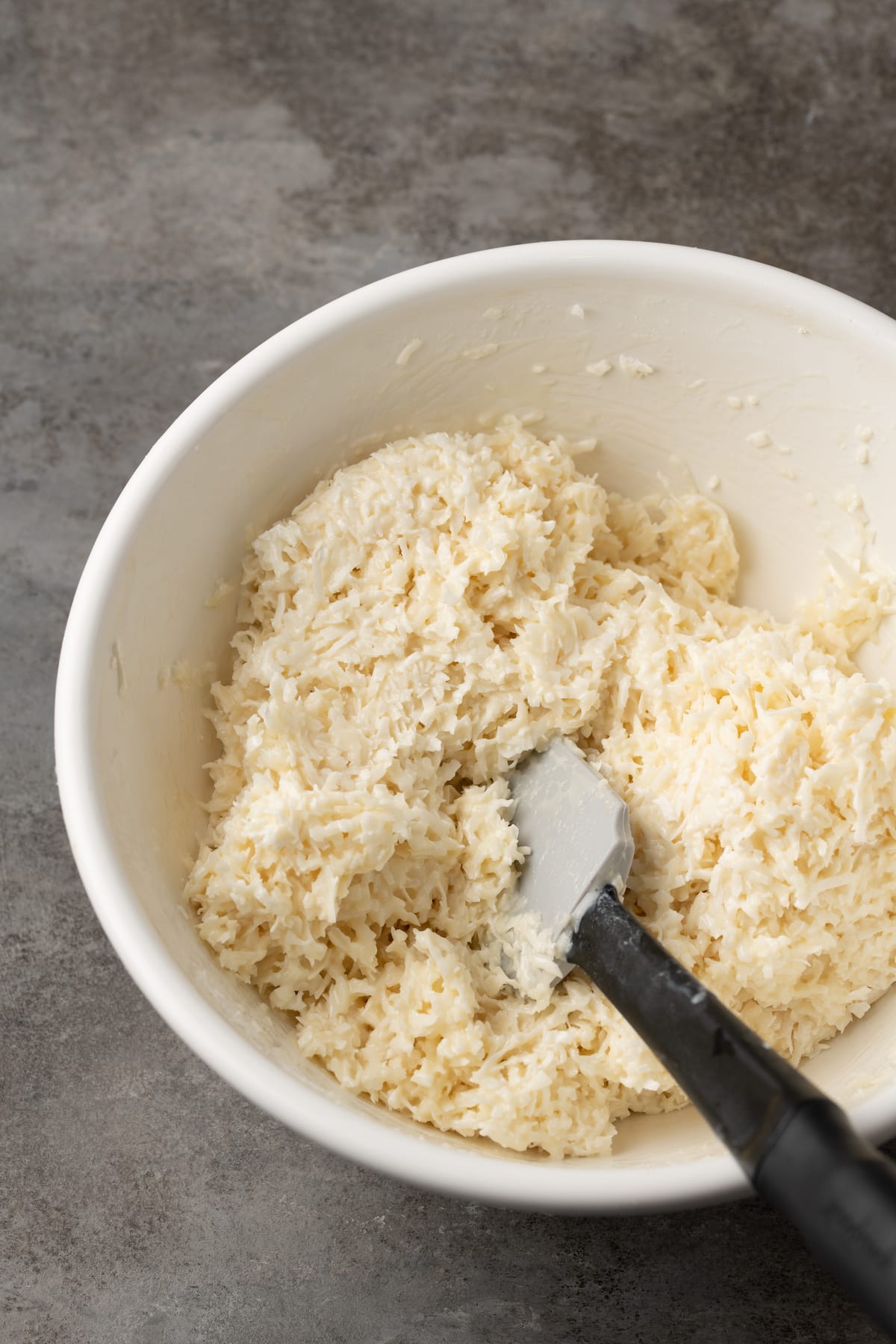 Coconut filling in a bowl with a rubber spatula.