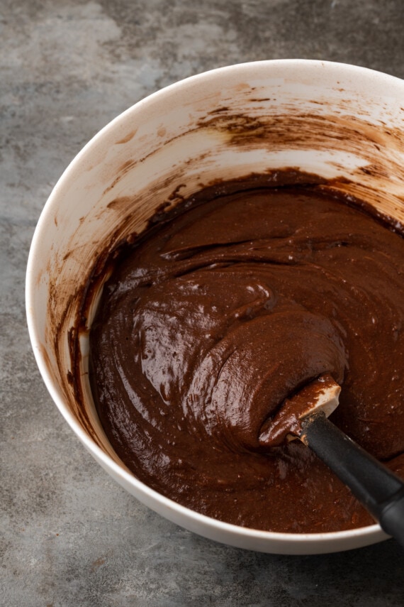 Brownie batter in a mixing bowl with a rubber spatula.