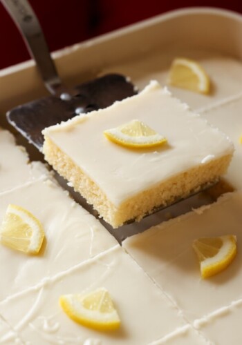 serving lemon cake on a spatula with a lemon wedge on top of the icing