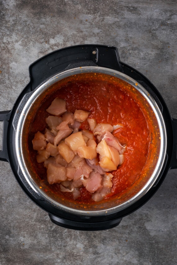 Chicken pieces added to the tomato sauce inside the instant pot.