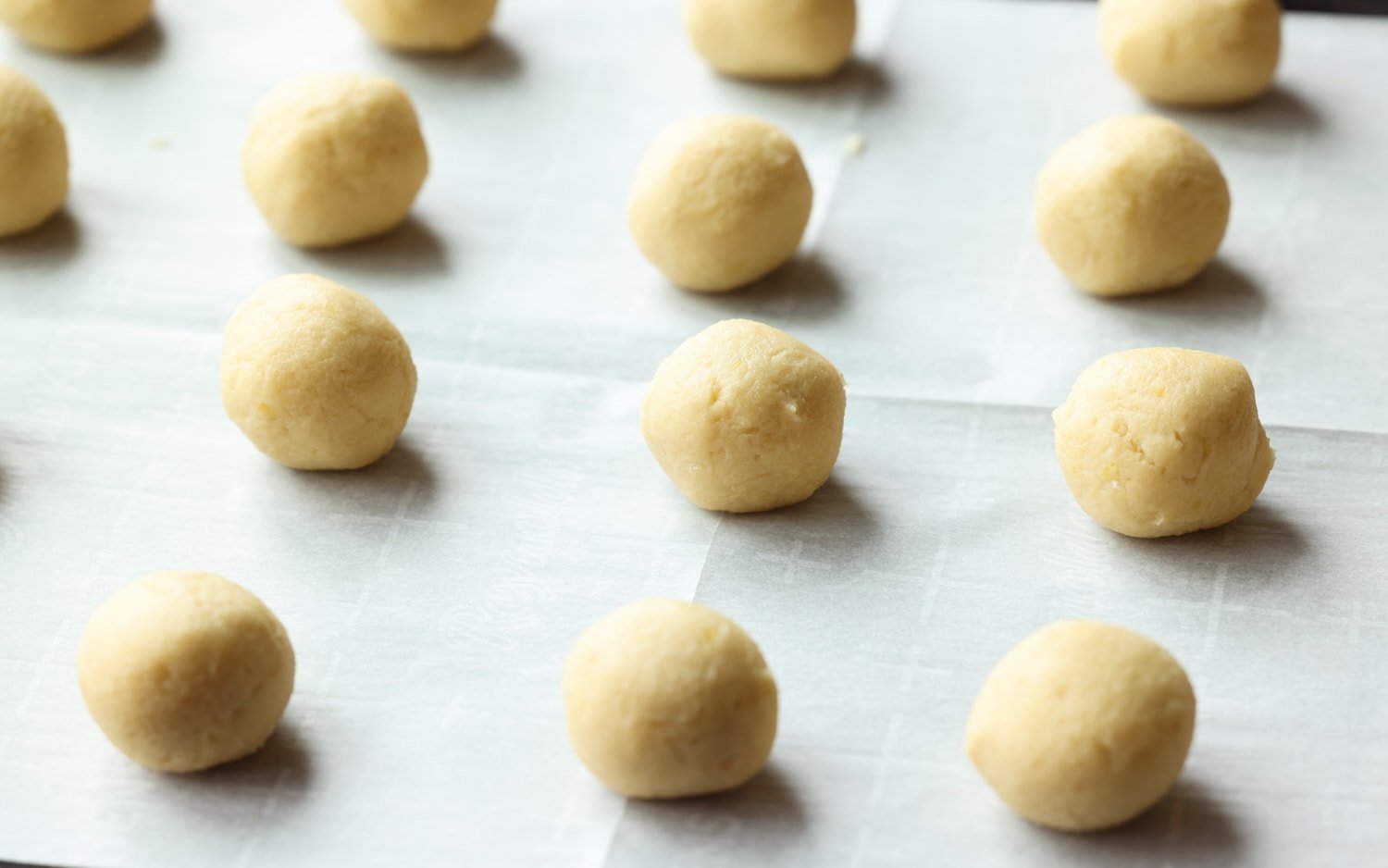 una bola de masa para galletas en un molde para pasteles forrado con pergamino