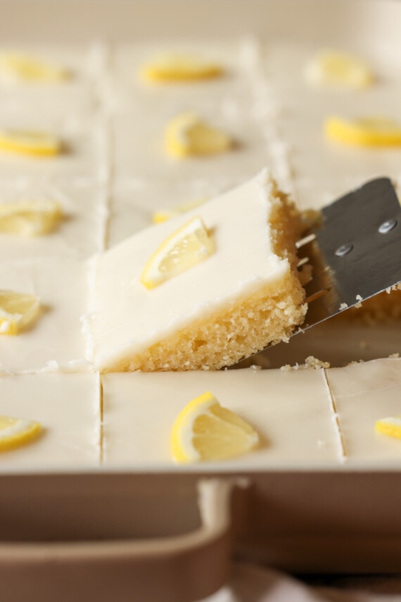 pulling a piece of lemon cake from the pan with a cake server