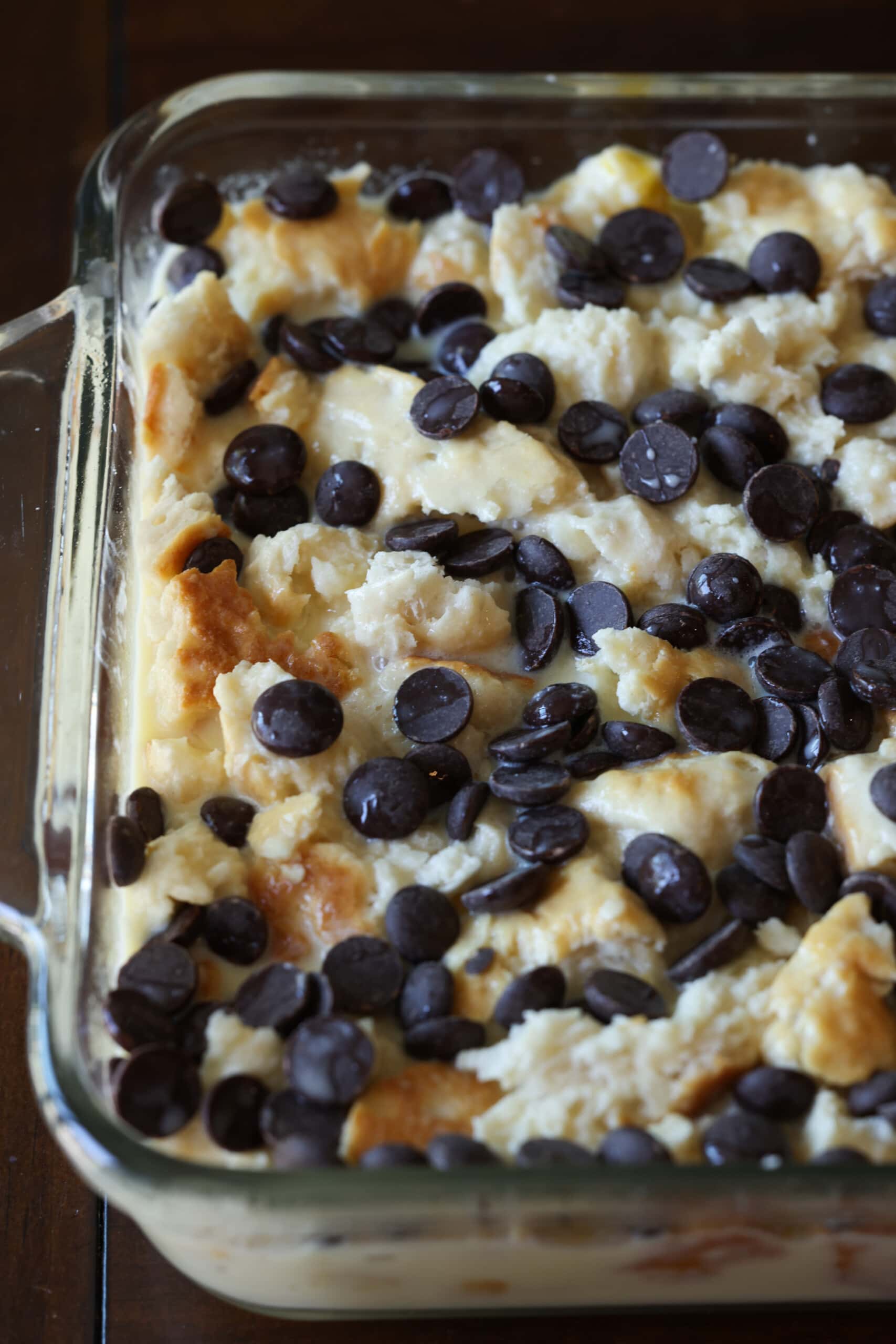 Day-old biscuits are torn into small pieces, dipped in the egg-custard mixture, topped with chocolate chips and baked in the oven.