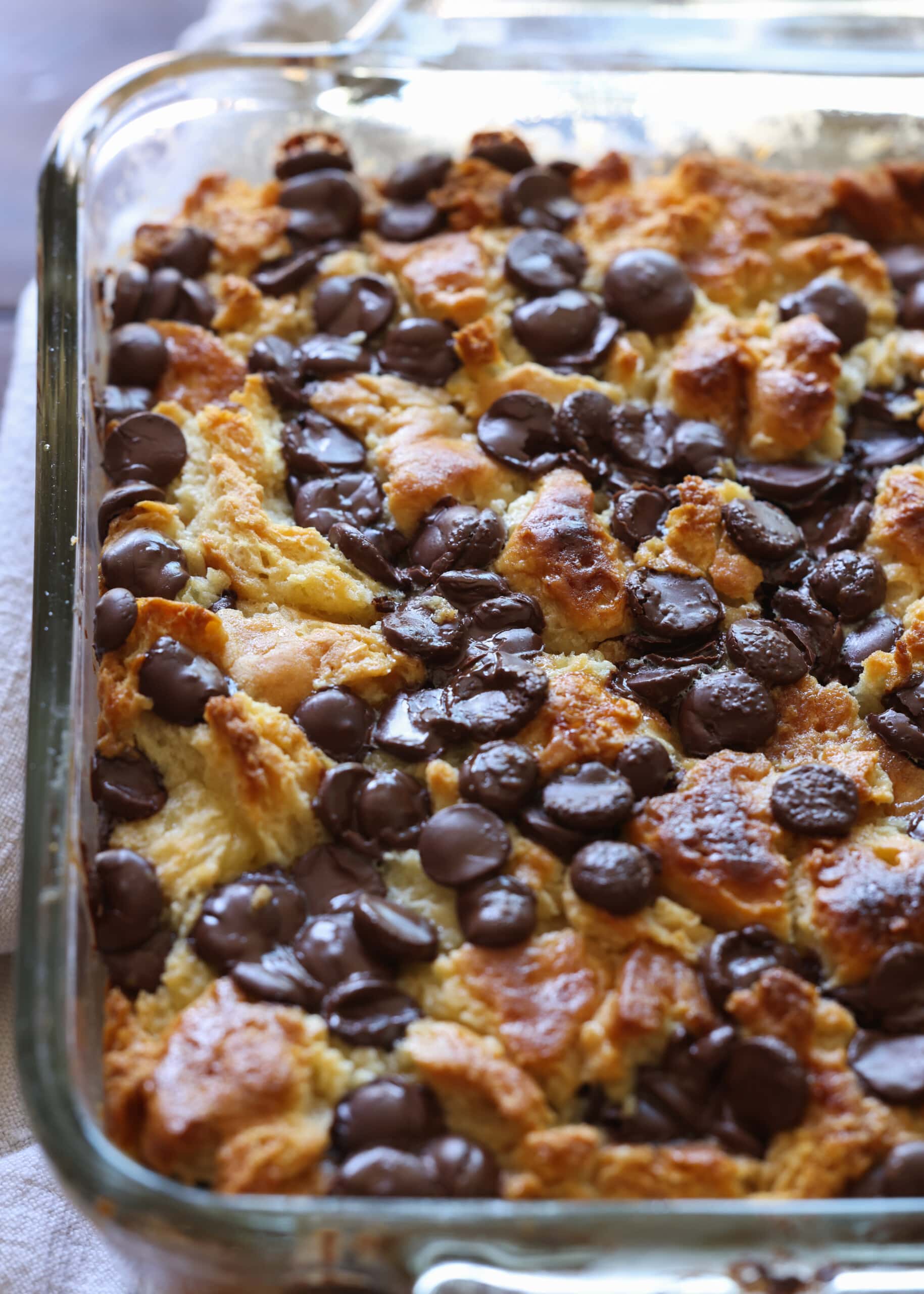 Bread pudding made with biscuits and topped with chocolate chips, baked in an 8x8 pan.