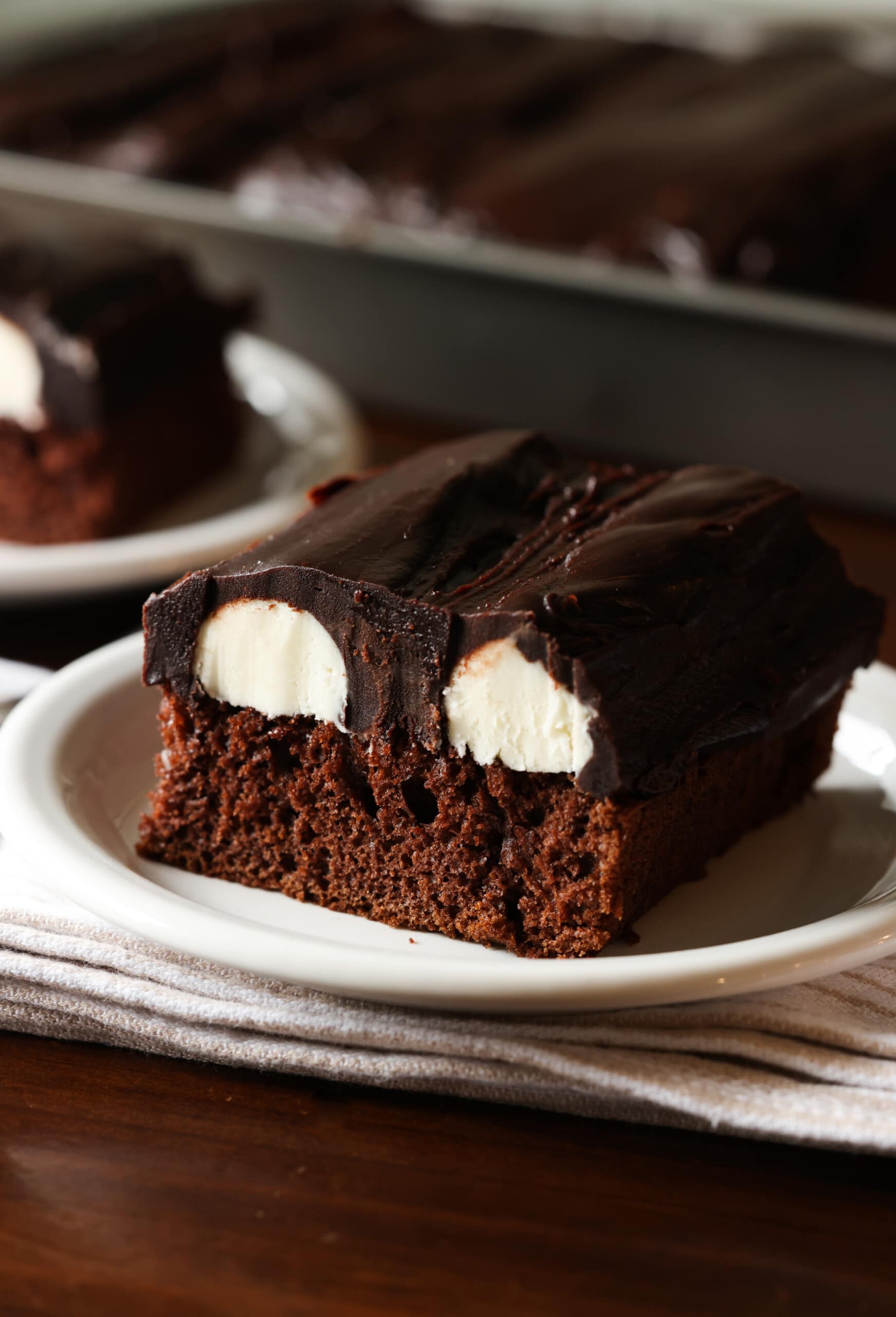 Chocolate devil's food cake topped with sliced ​​vanilla buttercream and chocolate ganache on a white plate