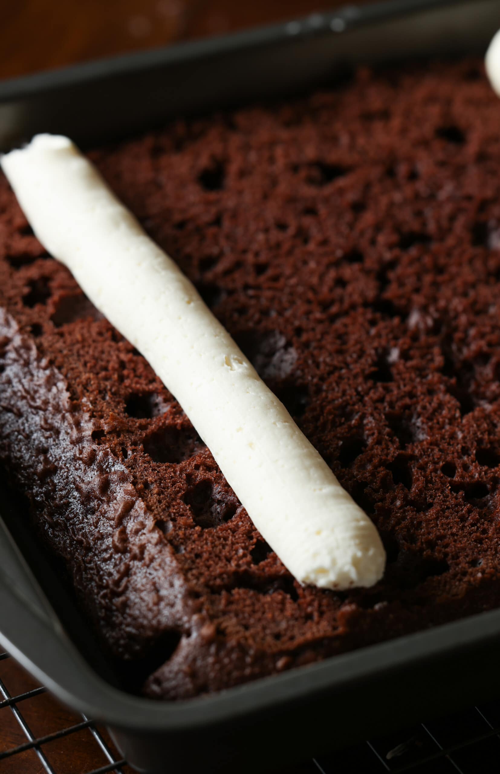 A piped tube of vanilla frosting on top of chocolate cake