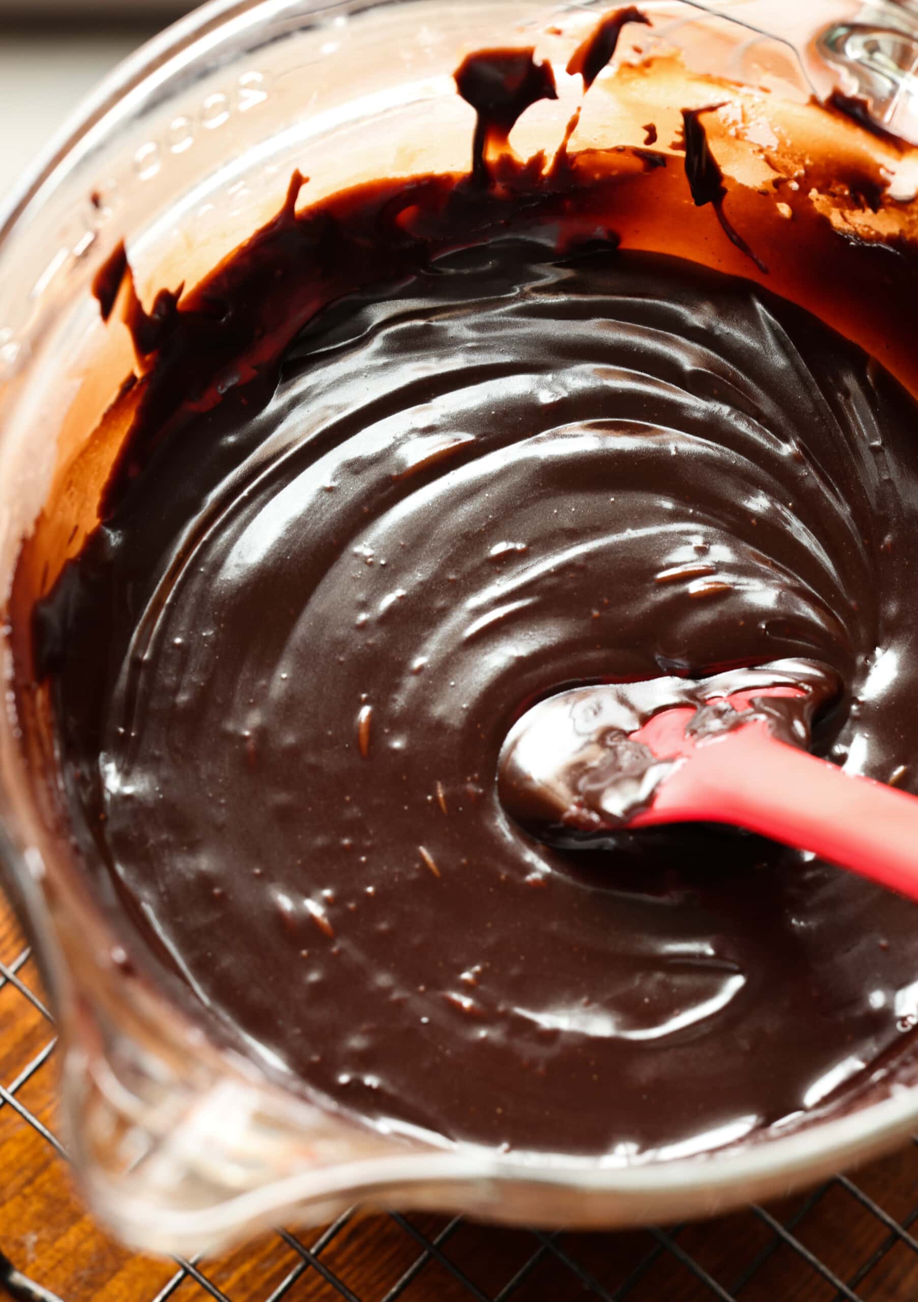 Chocolate ganache in a glass bowl with a rubber spatula