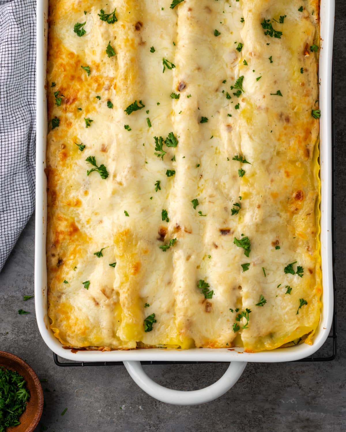 Overhead view of a baked chicken lasagna garnished with chopped parsley.