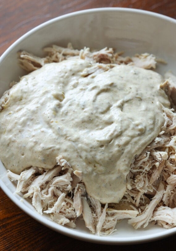 Sour cream enchilada sauce over shredded chicken in a white bowl
