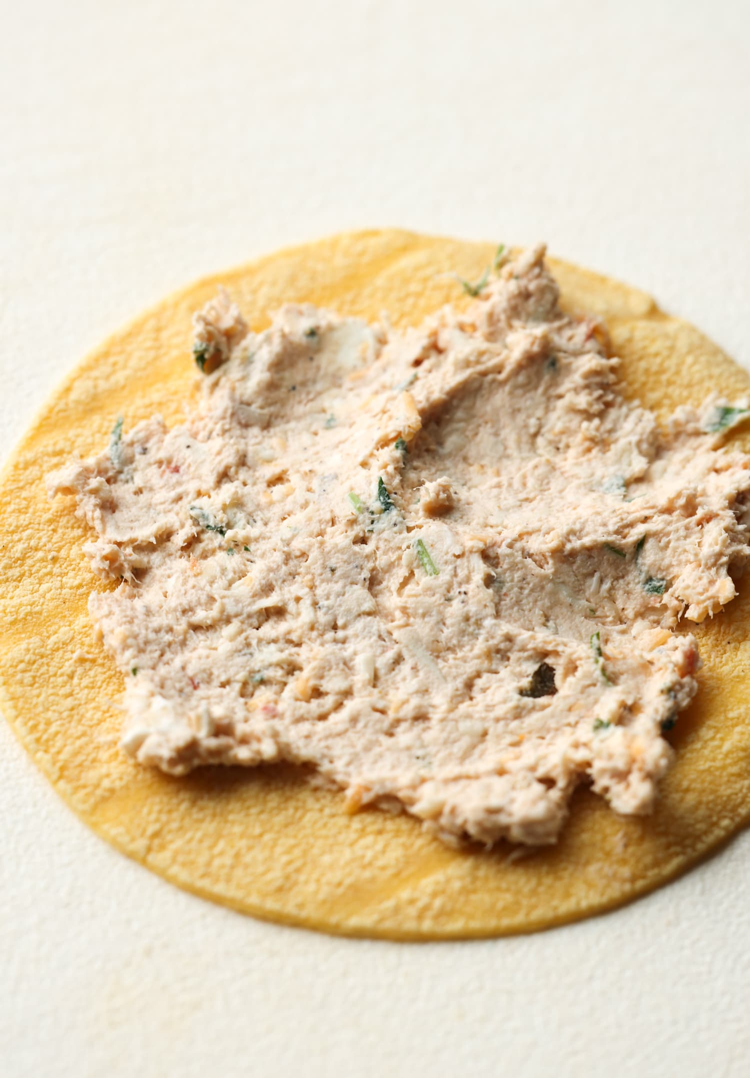 spreading chicken mixture onto a corn tortilla