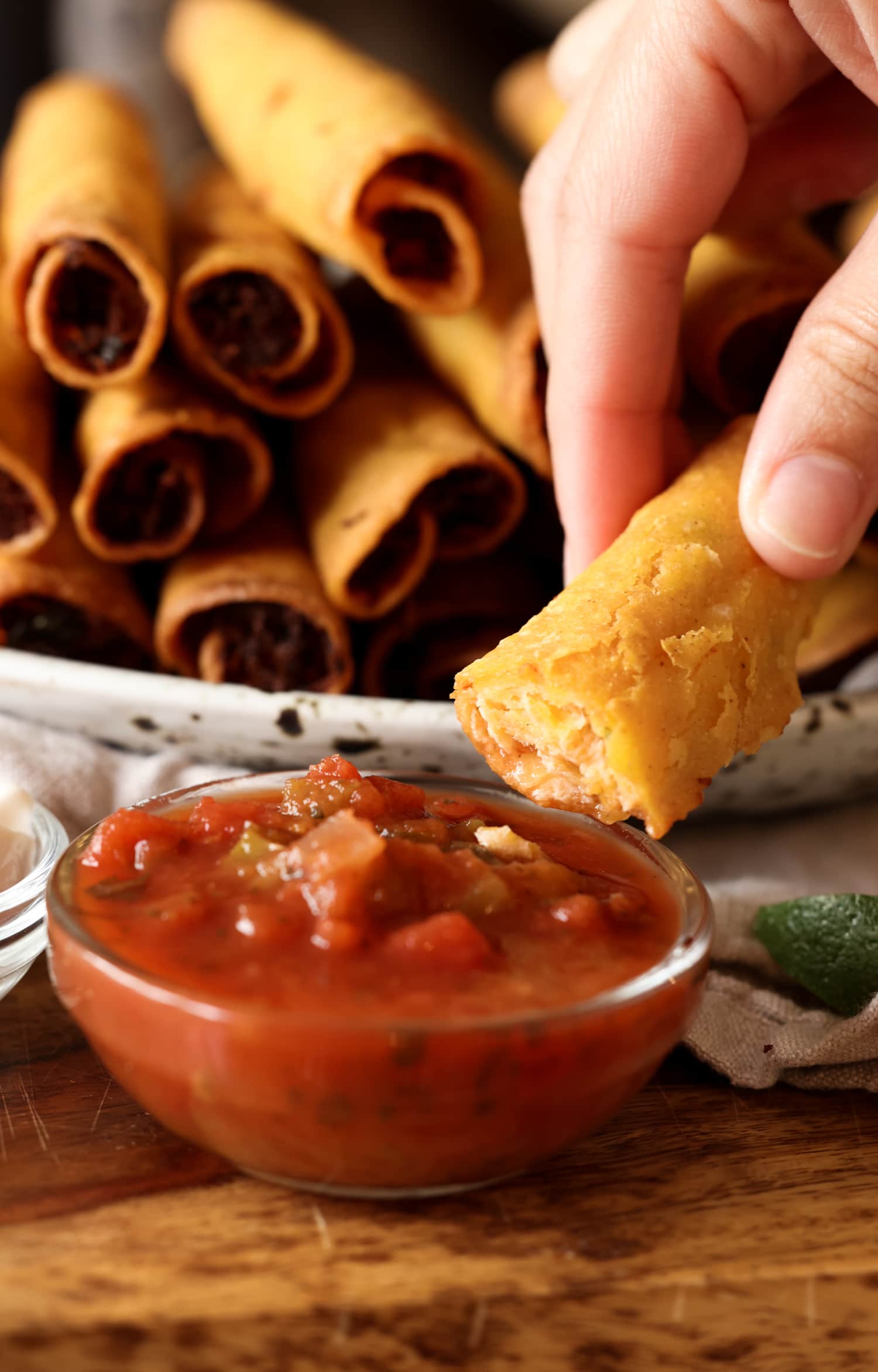 a taquito being dipped in salsa