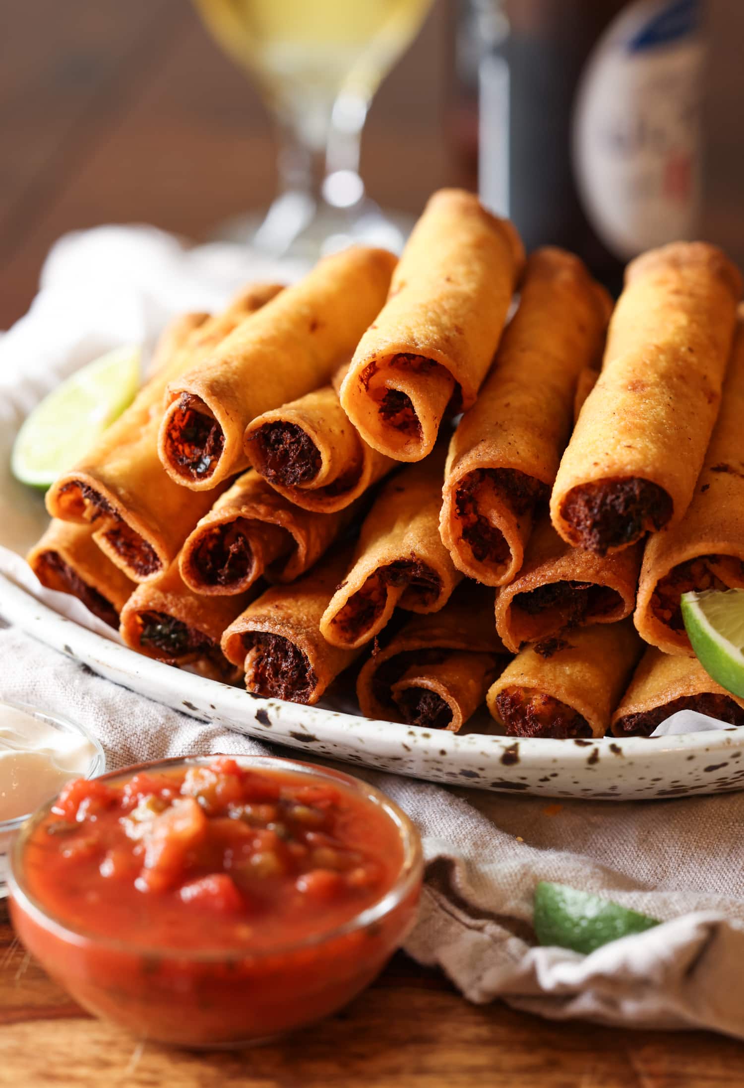 chicken taquitos piled on a platter with salsa to dip