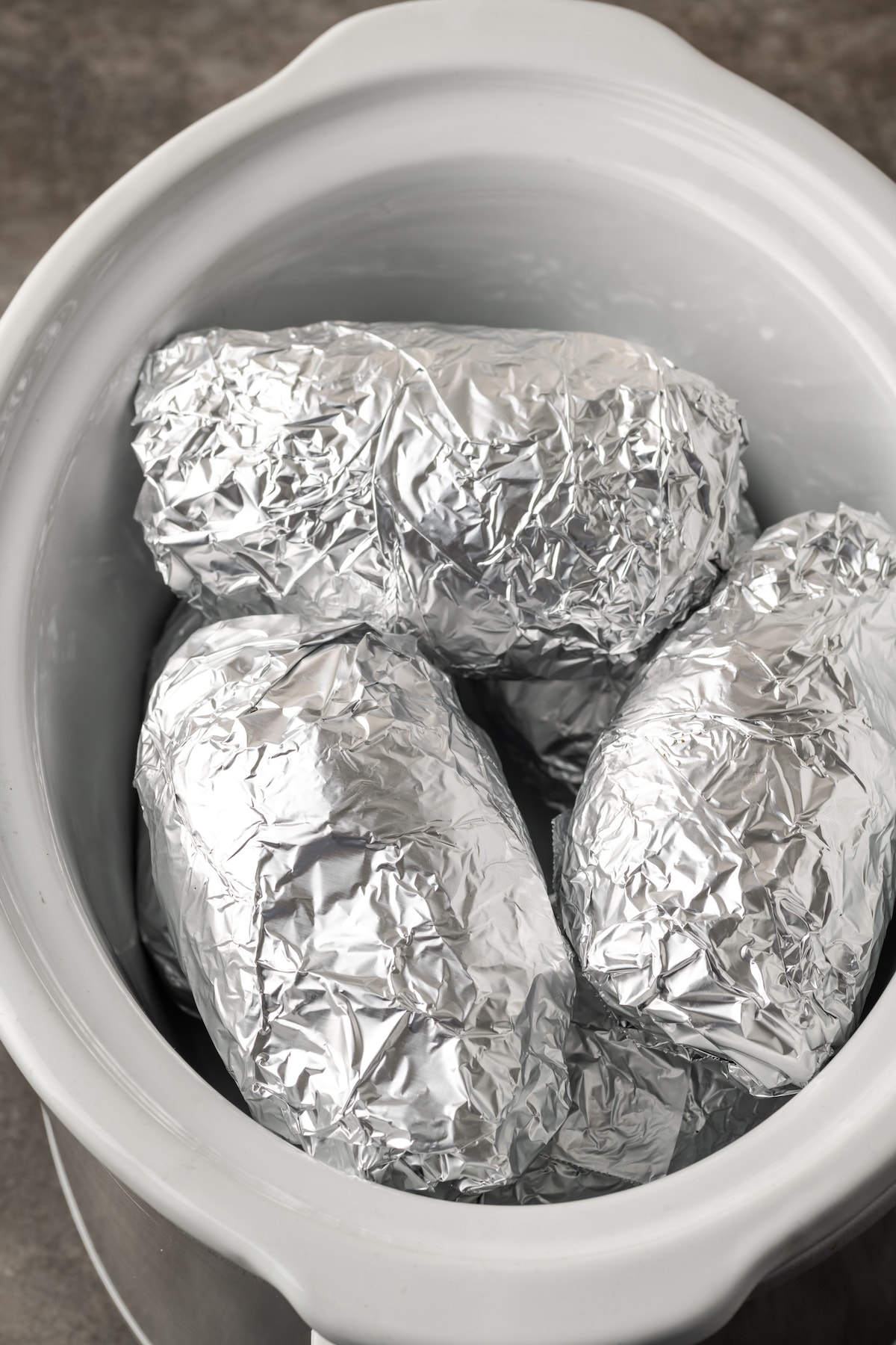 Foil-wrapped potatoes inside the crock pot.