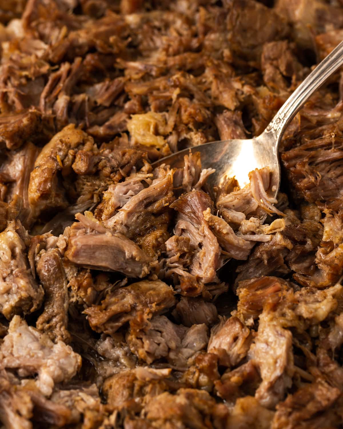 A fork stuck into Instant Pot carnitas on a metal baking sheet.