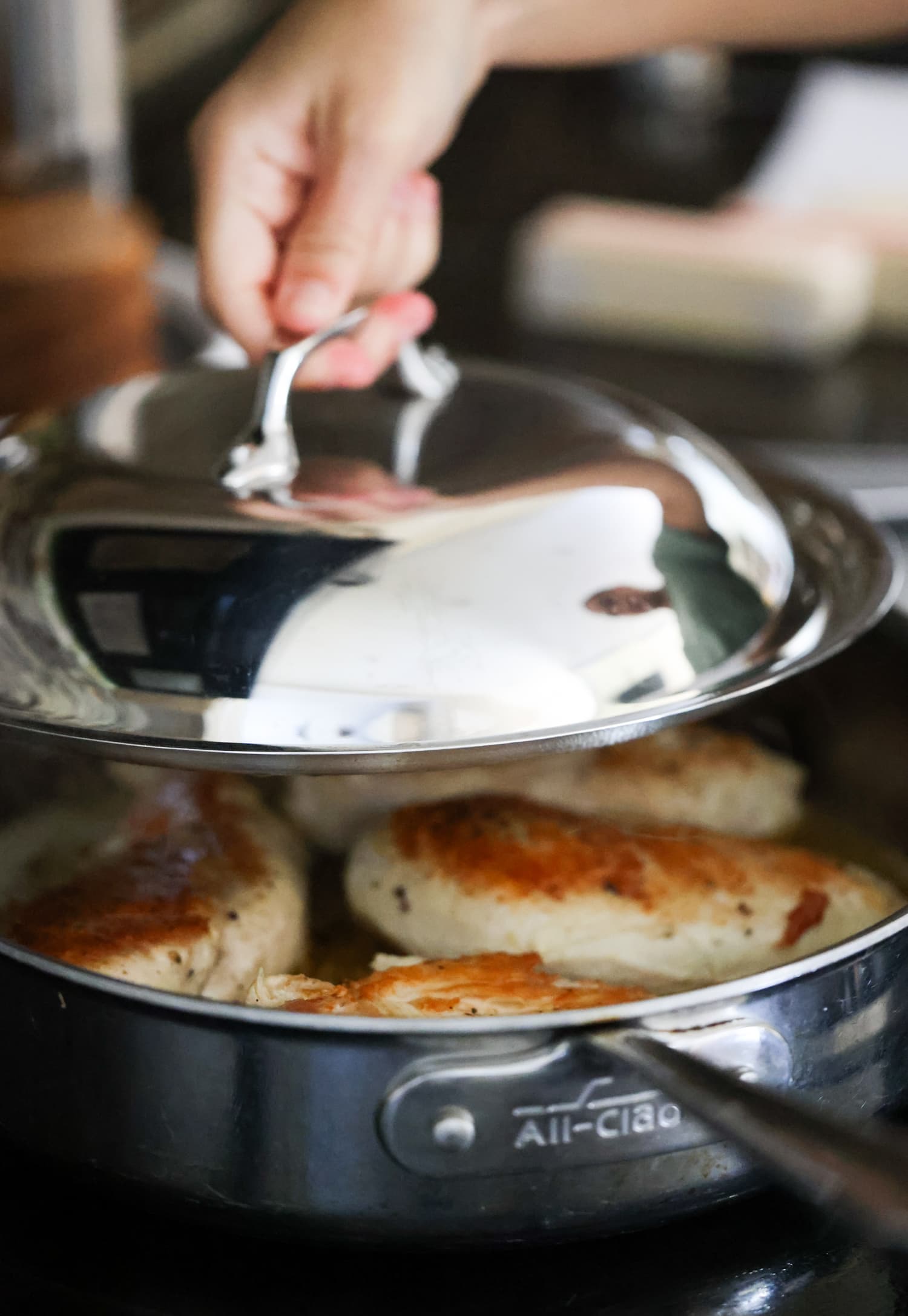 placing the lid on a skillet with browned chicken in the pan.