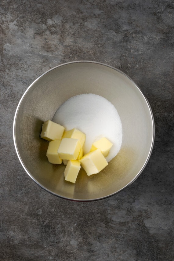 Cubed butter and sugar in a metal mixing bowl.