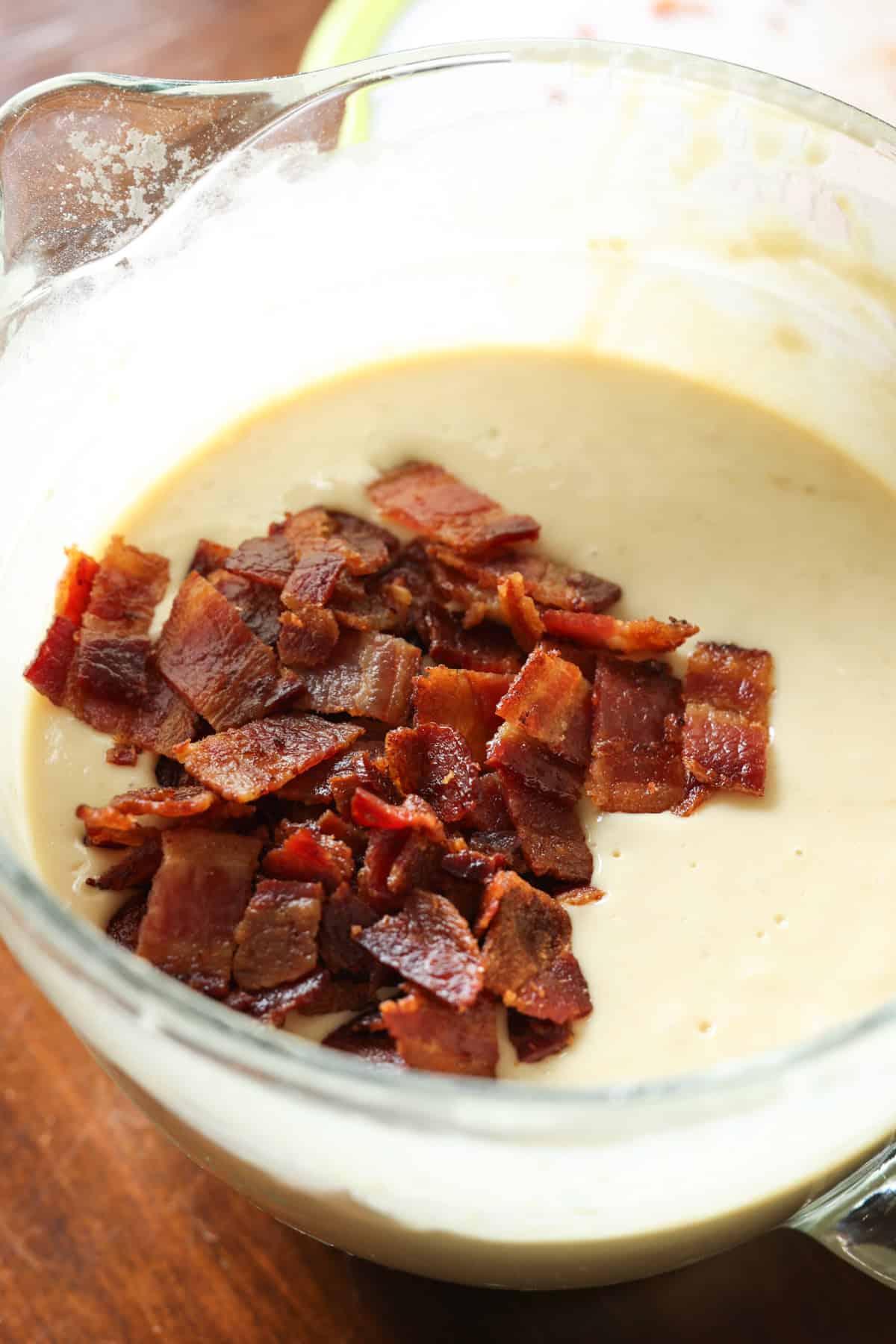 pancake batter in a clear glass bowl with chopped bacon