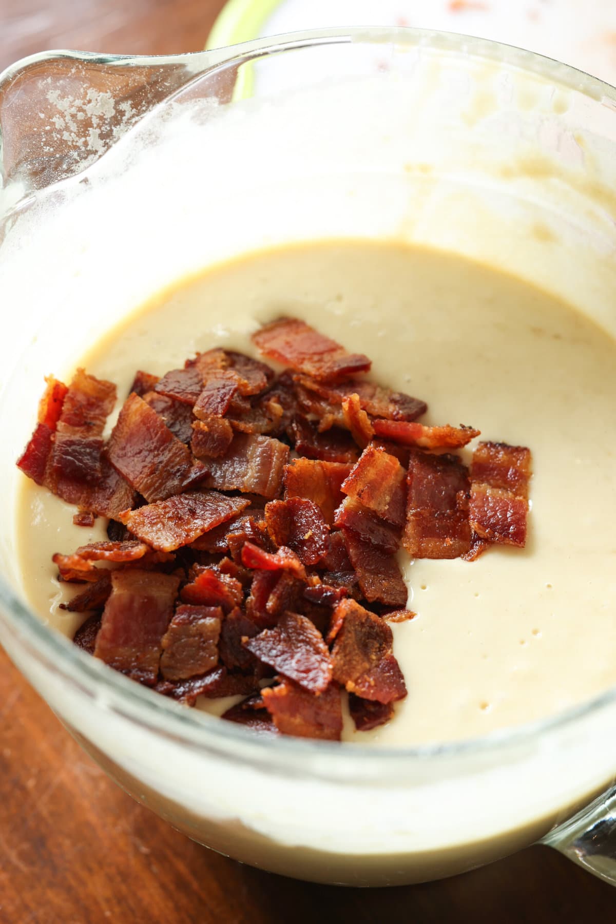 pancake batter in a clear glass bowl with chopped bacon