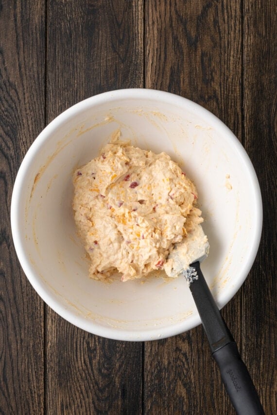 Pimento cheese stirred together in a white bowl with a spatula.