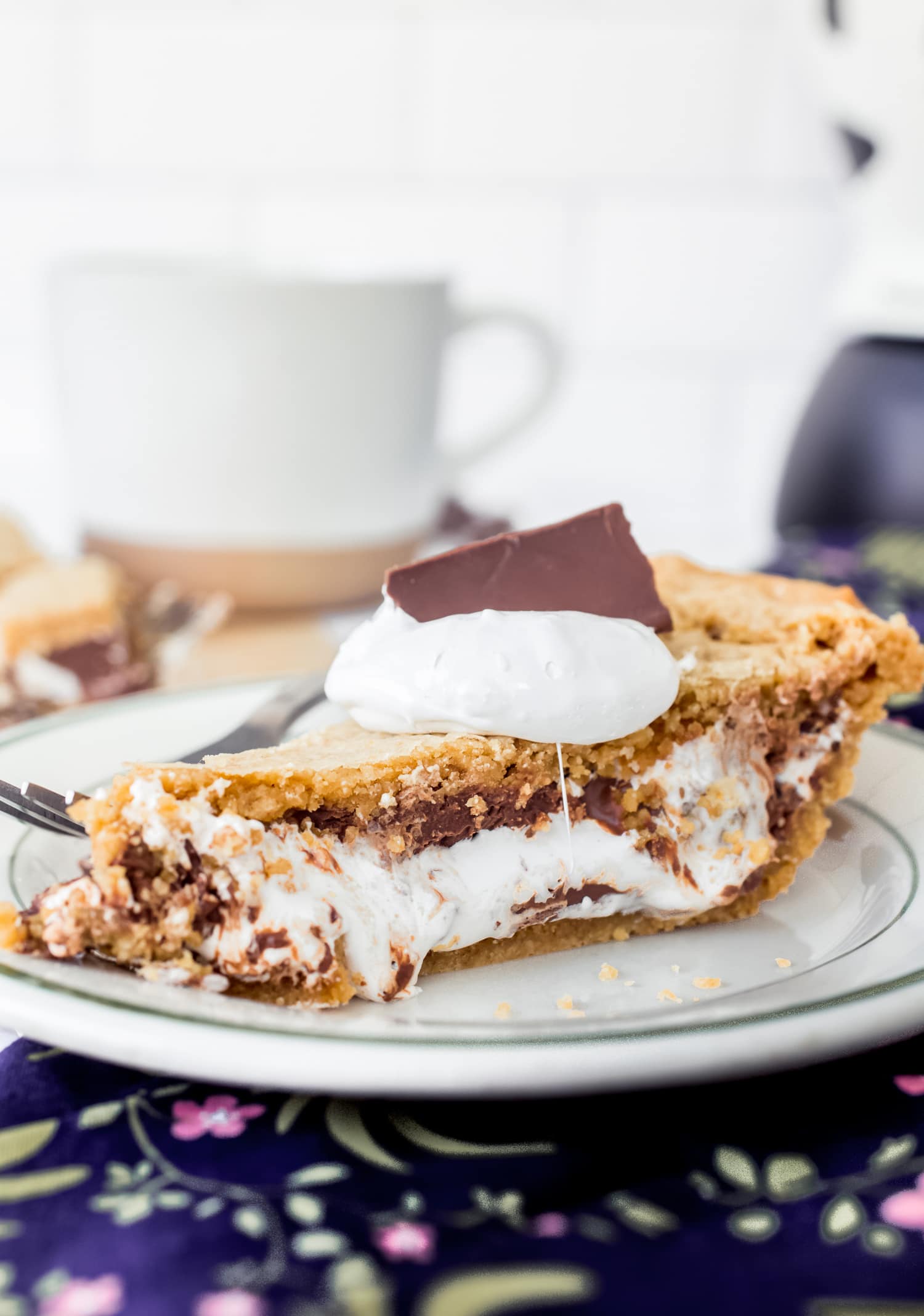 A slice of s'mores pie served on a plate topped with marshmallow cream and chocolate