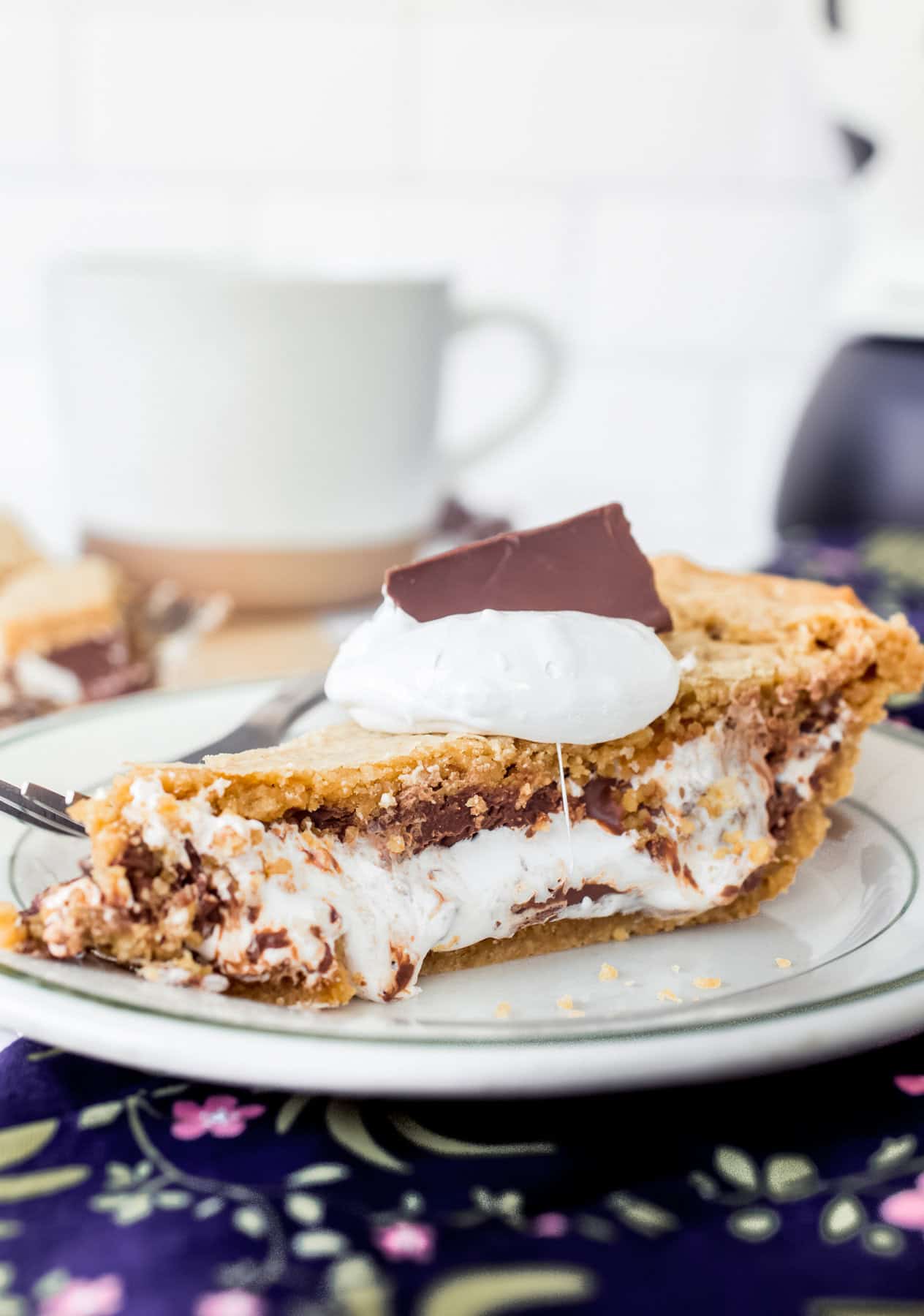 Ein Stück S'mores-Kuchen auf einem Teller, garniert mit Marshmallow-Creme und einem Stück Schokolade