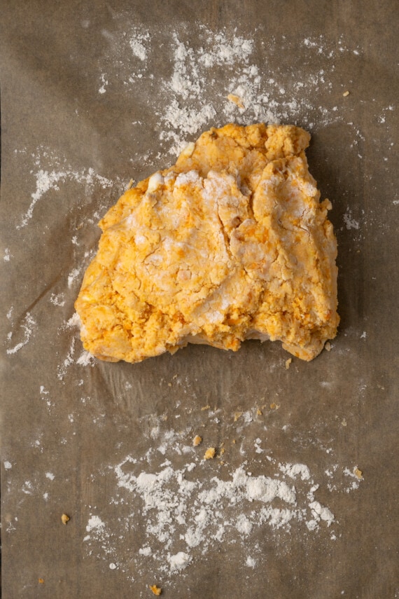 Sweet potato biscuit dough folded over itself on a floured surface.