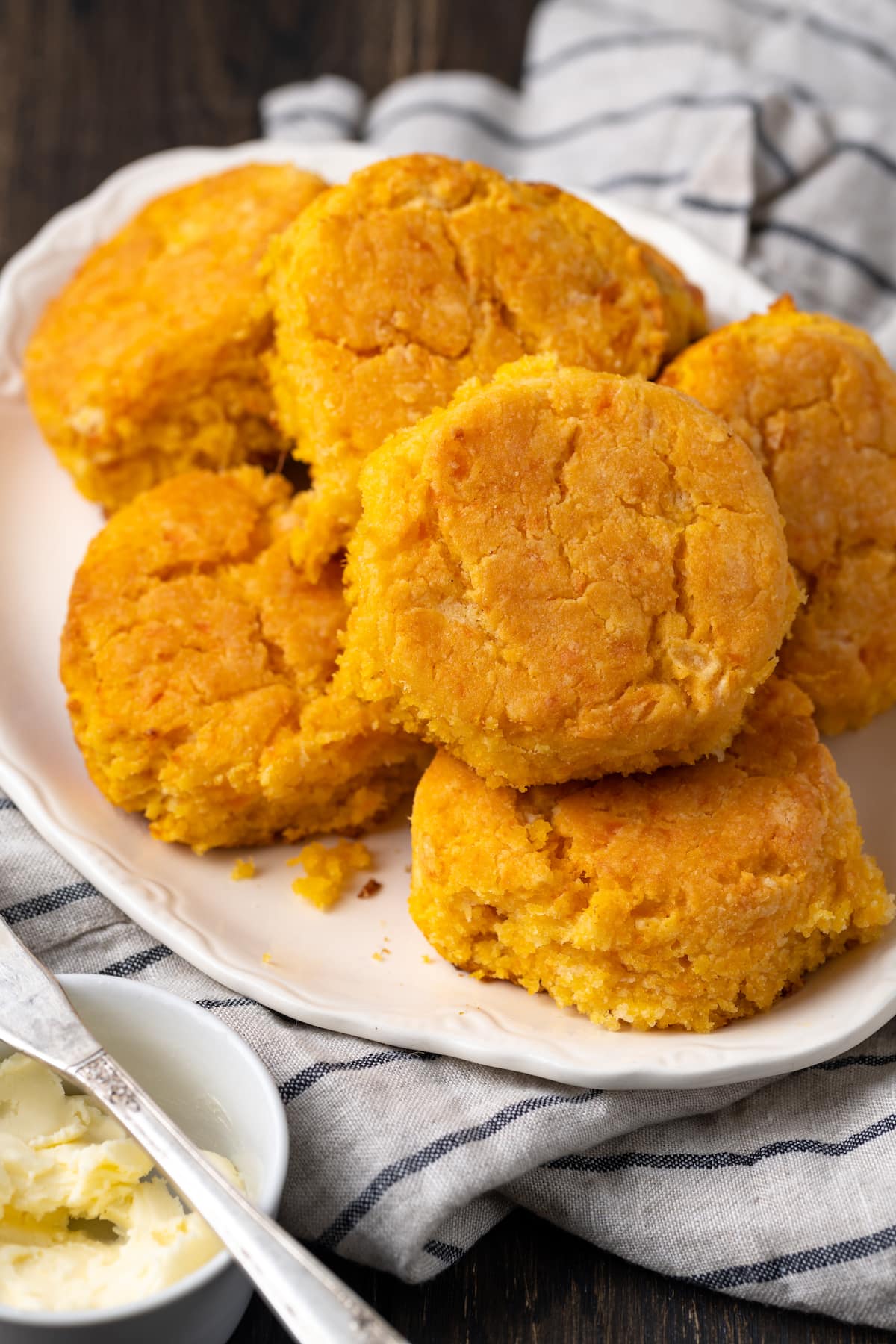 Sweet potato biscuits stacked in a pile on a white platter.