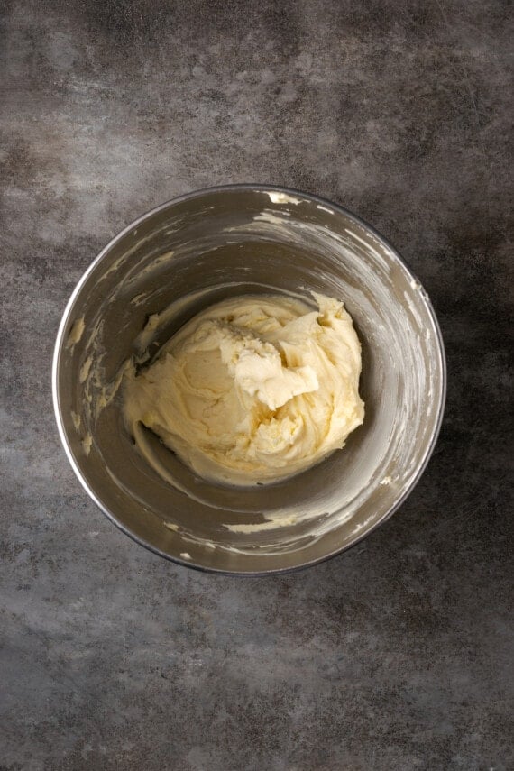 Cream cheese, butter, and sugar creamed together in a metal mixing bowl.