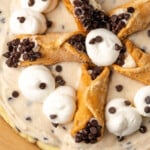 Overhead view of cannoli cheesecake decorated with swirls of whipped cream and mini cannoli pastries.