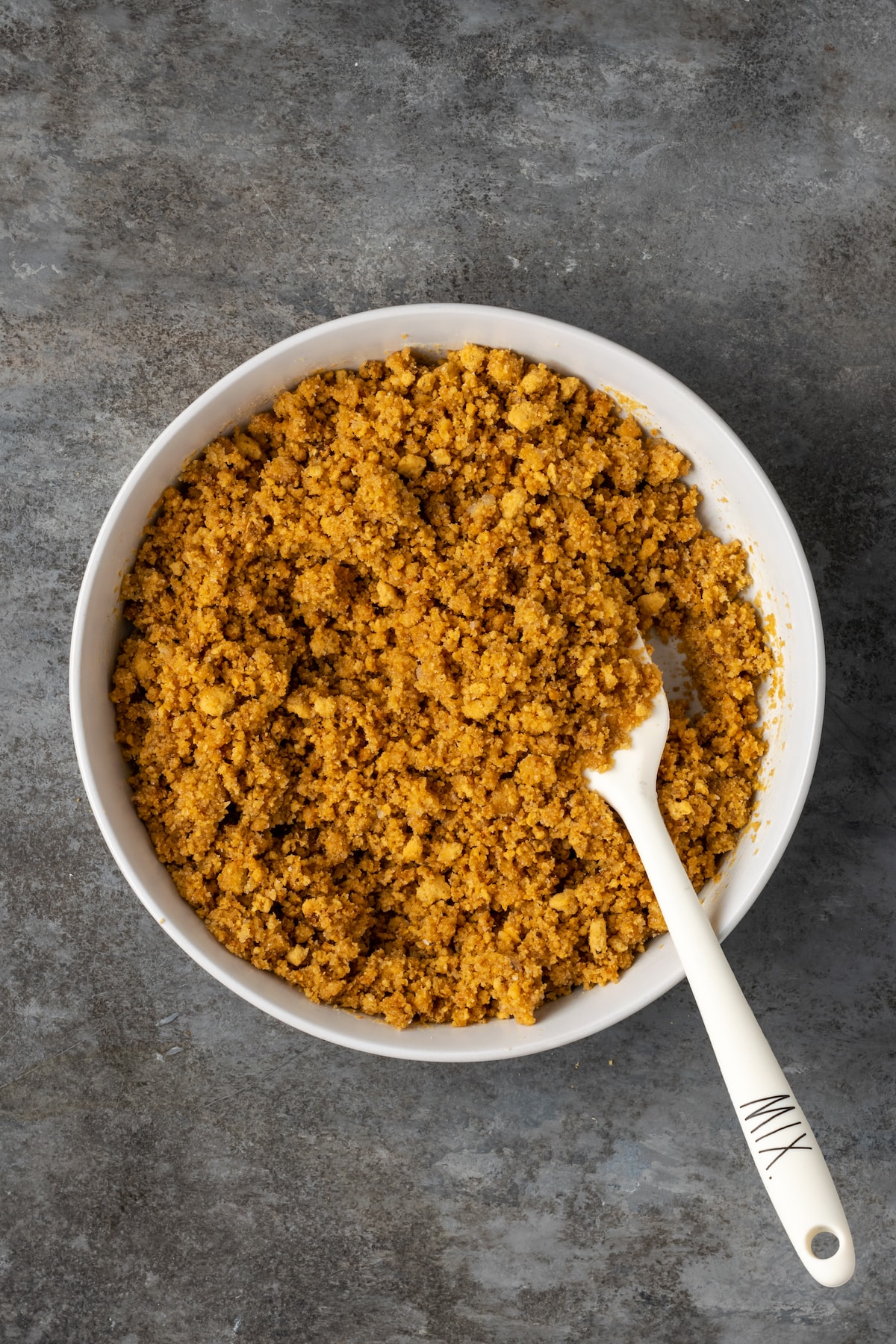 Graham cracker crust mixture in a bowl with a spoon.