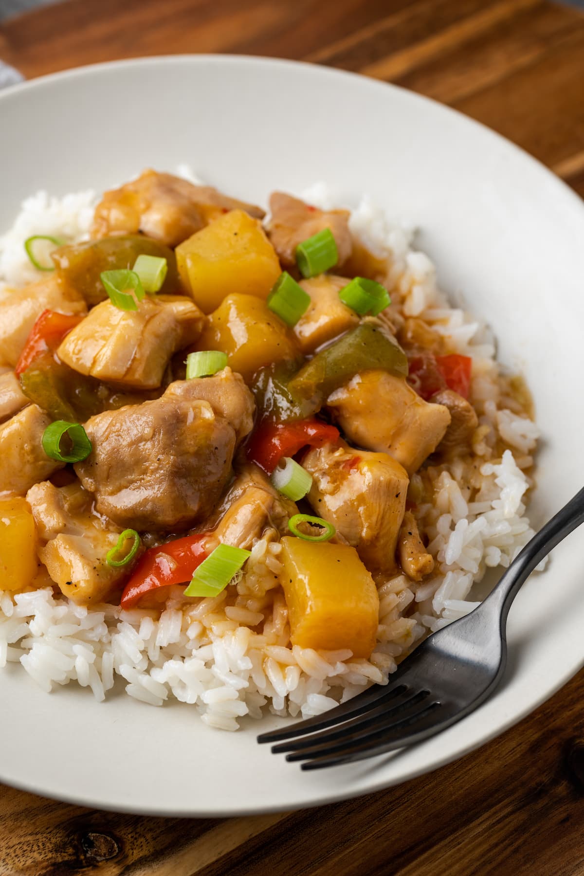 Instant Pot Hawaiian chicken served over rice on a white plate next to a fork.