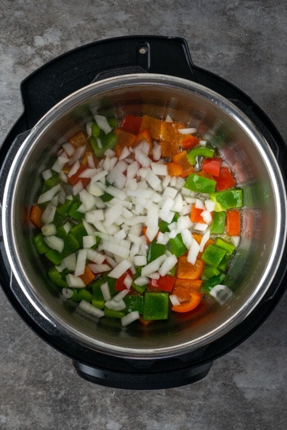 Diced onions added to the Instant Pot with red and green sauteed bell pepper chunks.