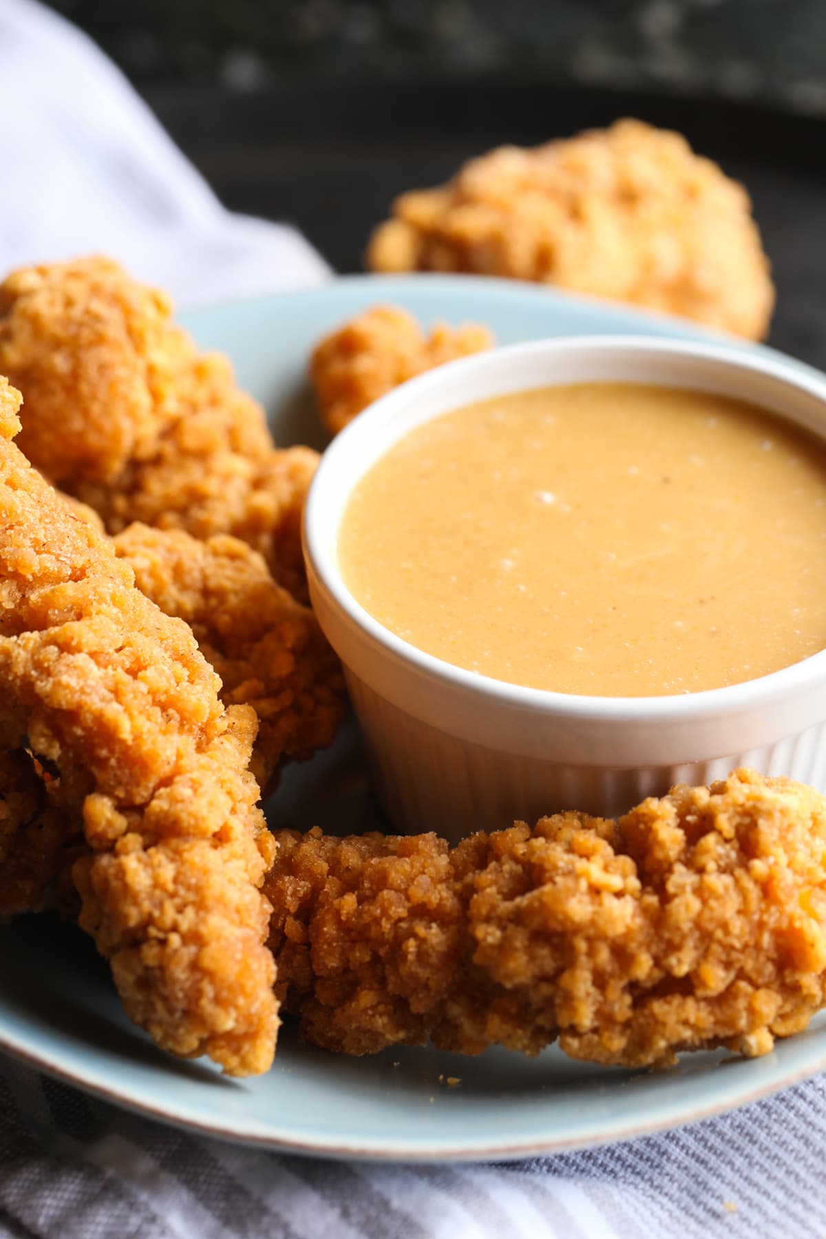 A bowl of homemade chicken dipping sauce on a plate with breaded and fried chicken tenders