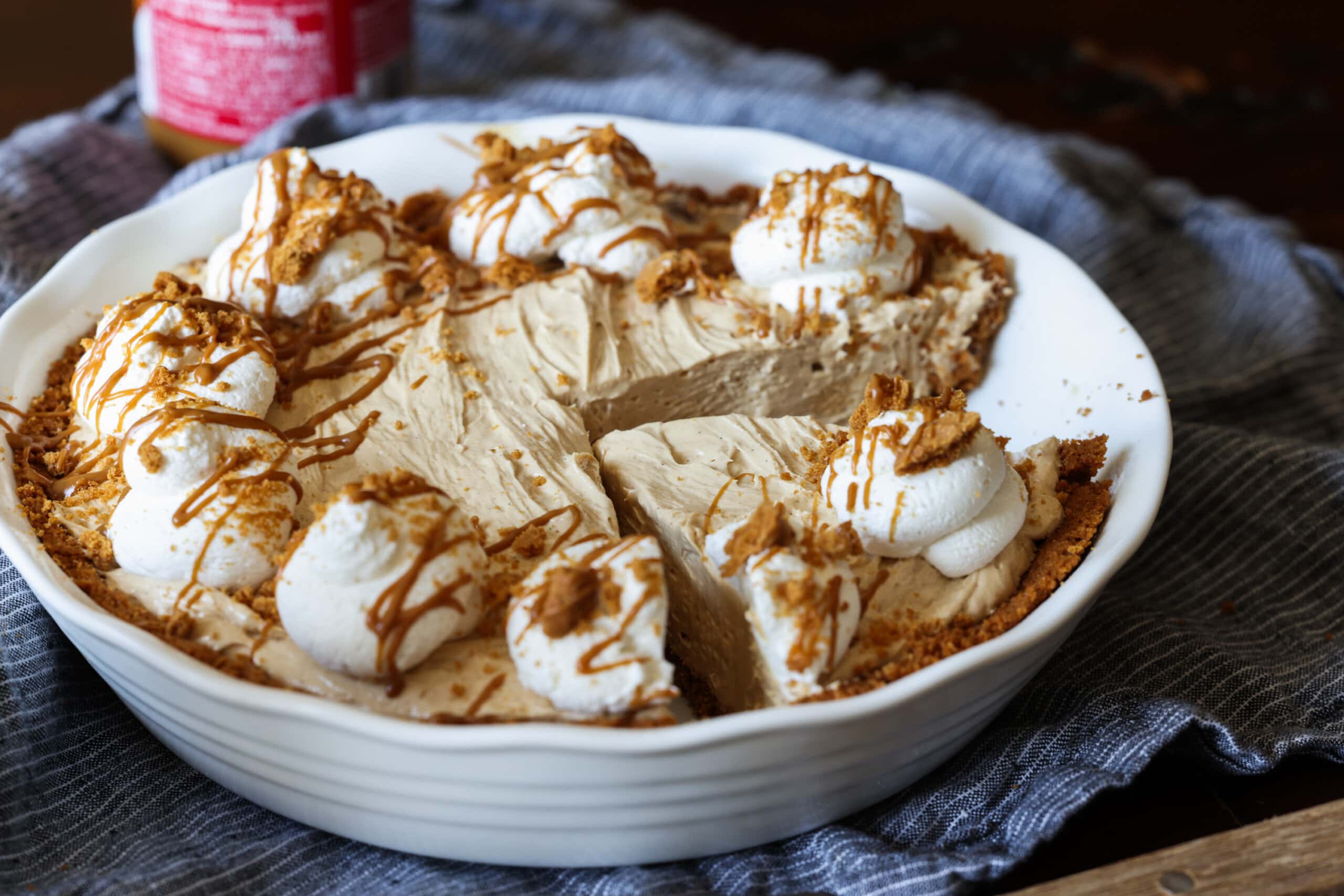 A biscoff mousse pie in a white pie plate with a slice cut