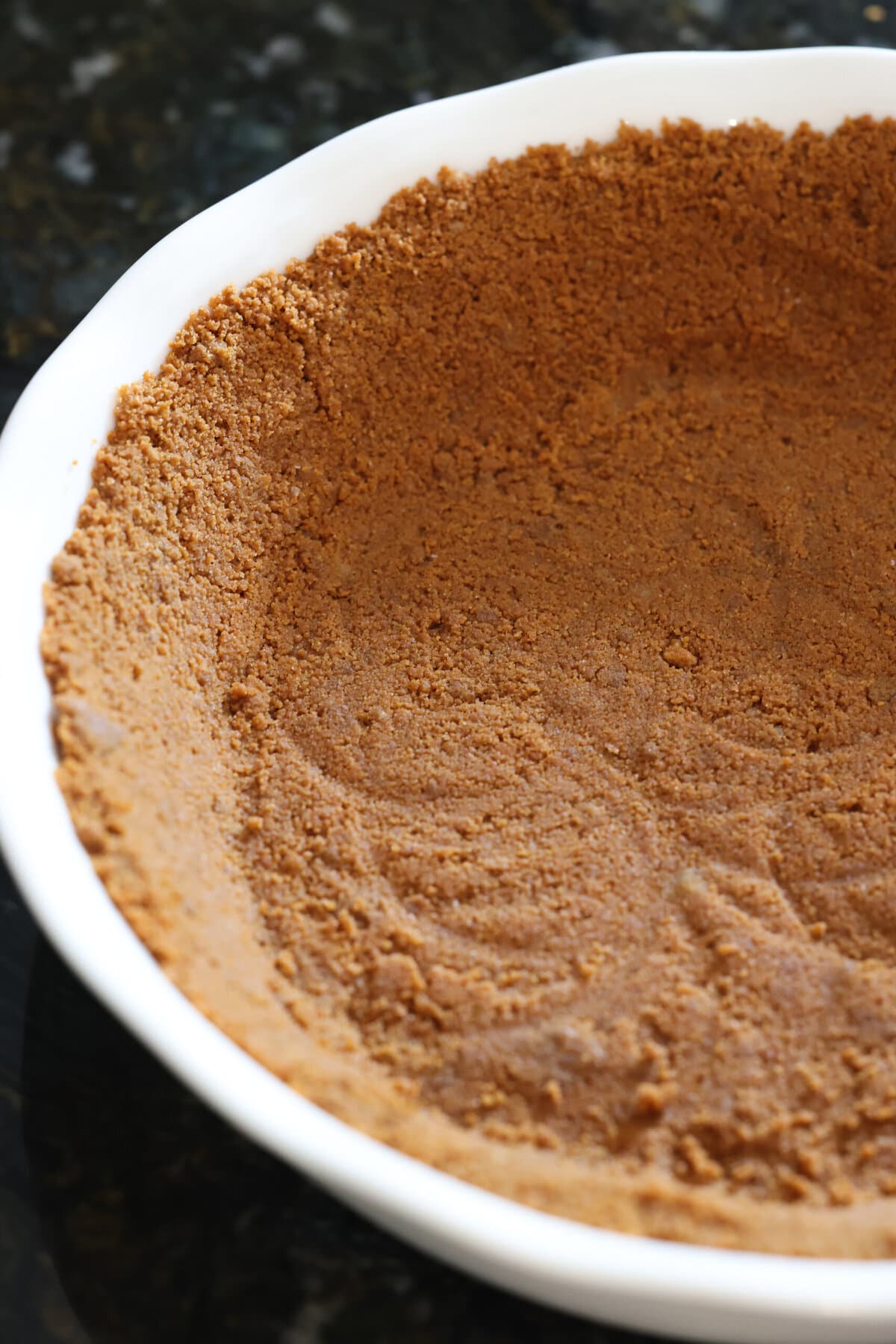 An unbaked cookie pie crust in a white pie dish