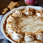 Cookie Butter pie in a white pie plate topped with whipped cream, crushed cookies, and drizzled Biscoff spread